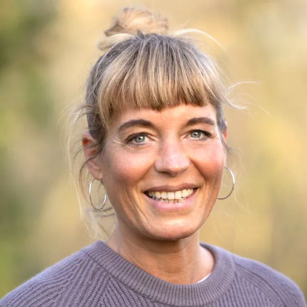 Porträtfoto von Luise von Kummer. Sie hat blonde Haare, am Hinterkopf zu einem Knoten geschlungen; auf die Stirn fällt ein Pony. Sie trägt einen lavendelfarbenen Pullover und lächelt offen in die Kamera.
